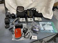 Group shot of all cameras, lens, chargers, cases and accessories on table