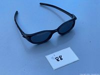 Front view of Oakley sunglasses with black frame and dark gray lenses