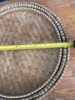 Three nested round bamboo trays with measuring tape showing diameter