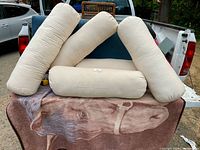 Five cream canvas bolster pillows on truck tailgate