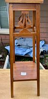 Full side view of tall wooden plant stand showing lyre cut-out and lower shelf