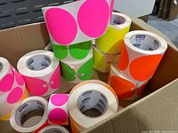 Assorted neon round dot label rolls and warning tapes inside box