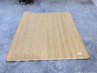 Full view of square natural fiber rug on concrete floor