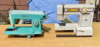 Front view of turquoise Domestic and off-white White 1505 sewing machines on table