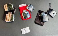 Three Zippo hand warmers with lids removed, showing finishes and branding