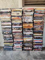 Six tall stacks of assorted DVD cases on concrete floor