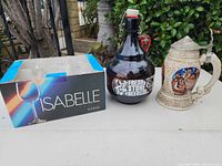 Front view of boxed Isabelle stem glasses, Stone Brewing growler, and Anheuser-Busch stein