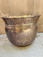Front view of hammered metal planter showing patina and scalloped rim
