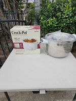 Boxed Crock-Pot slow cooker next to wrapped stainless stock pot on table