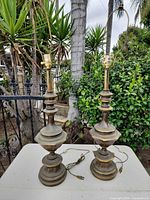 Full view of both brass lamps on table outdoors
