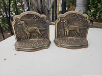 Front view of both brass bookends showing hunting dog relief and overall design