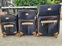 Front view of all three Steve Madden suitcases showing size comparison, black fabric, tan trim, spinner wheels