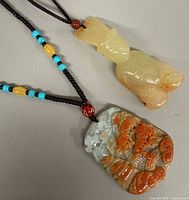Front view of both jade pendants with cords and beads