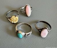 Four sterling silver rings laid flat to show stones and settings