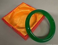 jade bangle resting on yellow satin lining in red box