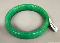 top view of green jade bangle with certification tag attached