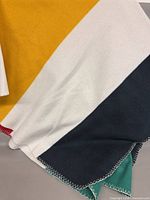 Overview of blanket showing yellow, white, navy, green stripes and stitched edge