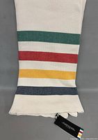 Folded blanket showing multicolour stripes and hang tag