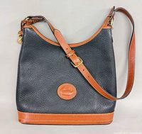 Full view of black pebbled leather bag with brown trim and strap