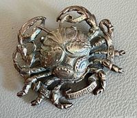 Front view of sterling silver crab brooch showing overall design and banner