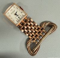 Full view of pendant watch brooch showing dial, woven connector and brooch bar