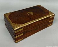 closed wooden box showing yin-yang inlay and brass corner straps