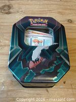 Front of Pokémon TCG metal collector tin with cards visible through window