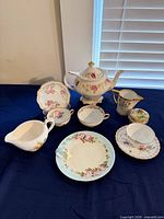 Group shot of all porcelain tea service pieces on blue surface