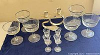 Full lot showing six coupe glasses, four etched cordial glasses, metal double candlestick holder