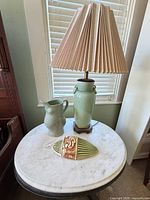 Table with marble top, lamp, pitcher and shell accent displayed