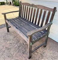 full view of wooden bench showing slatted seat, back, arms and legs