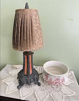 Lamp with shade, chamber pot and doilies displayed