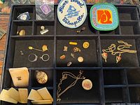 Overall view of tray with watch, locket, pins, rings, patches, tiles