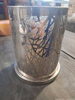 Front view of cylindrical metal candle holder showing branch cutouts and silver finish
