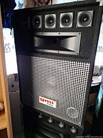 Front view of first speaker showing driver array and grille