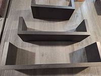 Top view of three black U-shaped floating shelves
