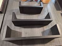 Three black U-shaped floating shelves, top view showing graduated sizes