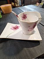 Side view of teacup, saucer and spoon displaying overall design and floral pattern