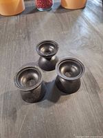 Three black rubber candle holders on tabletop