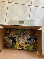 Box of Pokémon cards on scale showing weight