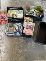 Overview of three tins and stacks of Pokémon cards