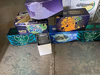 Multiple Elite Trainer Box shells and Pikachu tin on floor
