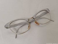 Angled view showing front and side of eyeglasses, silver aluminum brow, gold rims