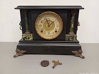 Front view of mantel clock with key and pendulum
