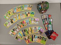Overview of mixed Pokémon cards arranged in arcs, code cards stack and metal tin