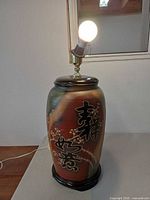Lamp lit showing pottery body, socket and wooden base