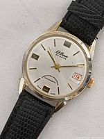 Dial side showing brand, date window, gold markers and hands