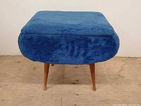 Front view of blue velvet ottoman showing upholstery and two front tapered legs