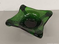 Top angle of emerald green Murano glass bowl showing free-form lobed rim and bubble inclusions