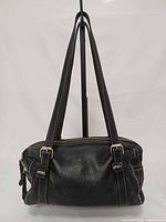 Front view of black leather Roots shoulder bag showing handles, texture, hardware